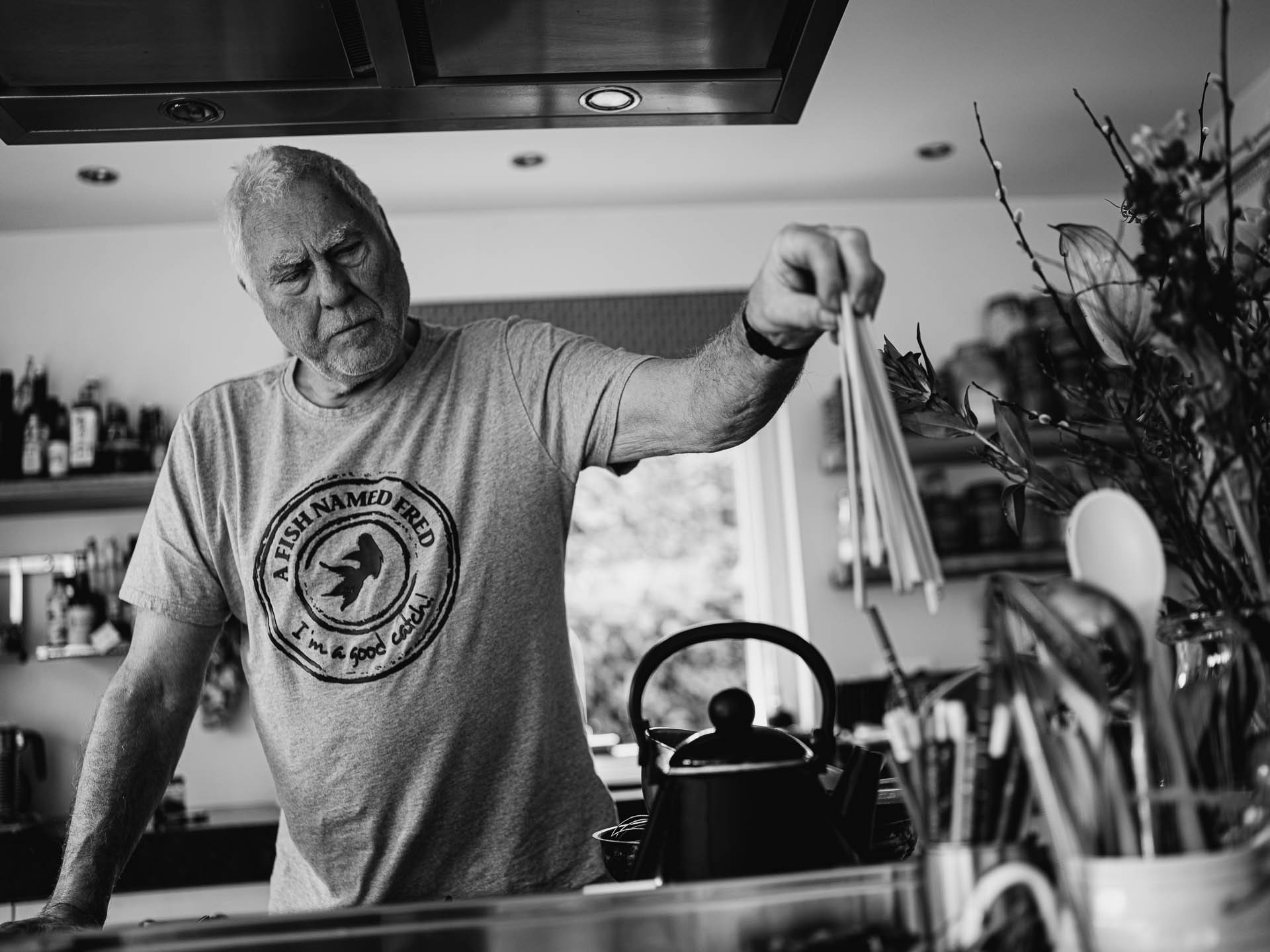 Black-and-white documentary photograph of a man in a kitchen, photographed by Cas van Laar.