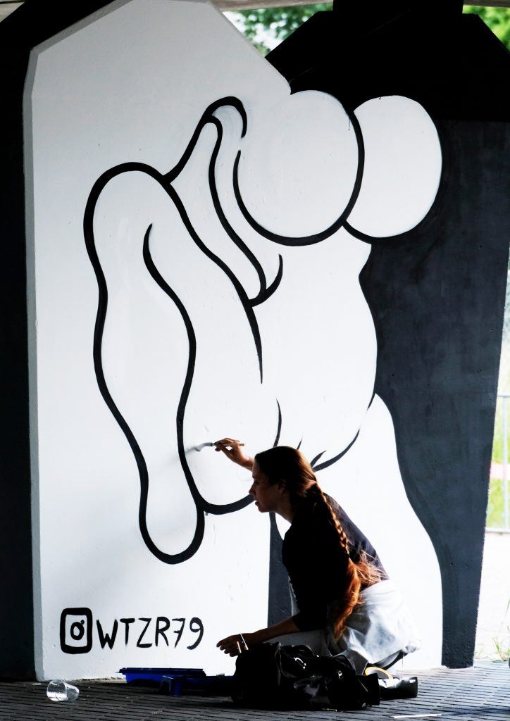 Hanneke Wetzer working on a large black-and-white mural.