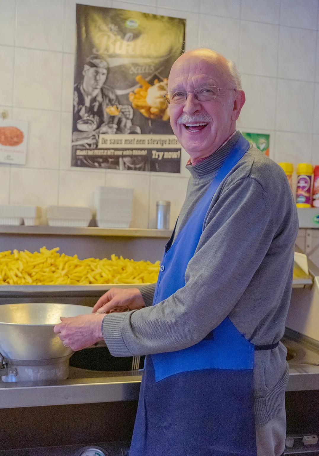 Snackbarhouder aan het werk achter de balie bij een bak friet.